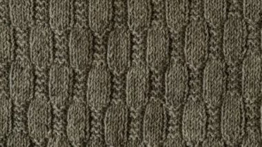 Gri örülmüş süveter parçasının desenli videosu. Örgü yapraklı arka plan, kabloyla örgü deseni. Üst manzara, yakın plan. El yapımı yün ya da pamuk kumaş dokusu. 