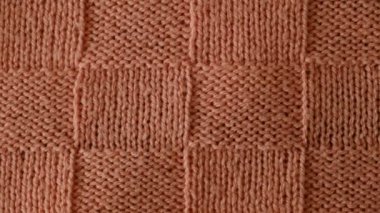 Örgü süveterin desenli bir görüntüsü. Üst manzara, yakın plan. El yapımı yün ya da pamuk kumaş dokusu. Alışılmadık soyut örülmüş satranç desenli arkaplan dokusu. 