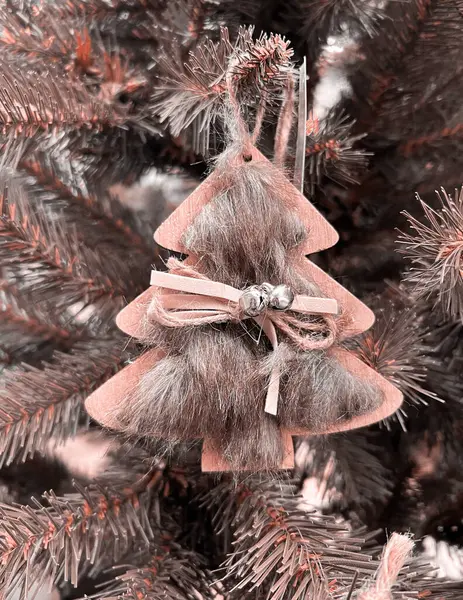 Zero waste. Eco Christmas tree decor toy - wooden pendant is decorated with fur, ribbon and bell, without plastic. Color Of The Year 2024 - Peach Fuzz.