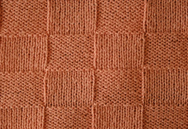 Texture of smooth knitted sweater with pattern. Top view, close-up. Handmade knitting wool or cotton fabric texture. Unusual abstract knitted chess pattern background texture.