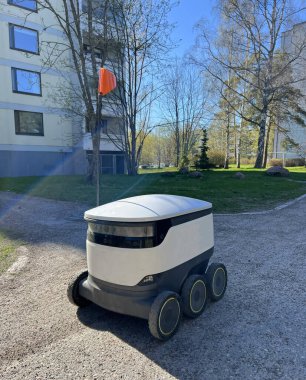 İkamet alanındaki kaldırımda paketleri teslim eden otonom dağıtım robotu. Gelecek kavramı, teknoloji, insansız kurye robot..