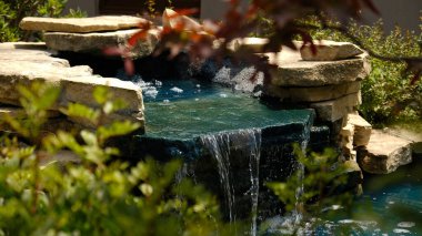 Geleneksel bir Japon bahçesinde mini bir şelale. Taşlardan yapılmış dekoratif şelale ve peyzaj tasarımı için küçük bir gölet.