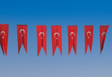 Many Turkish flags hanging at street against blue sky, ready to national holiday celebration. Street party decorations in Turkish city. Flags are fluttering in the wind. clipart