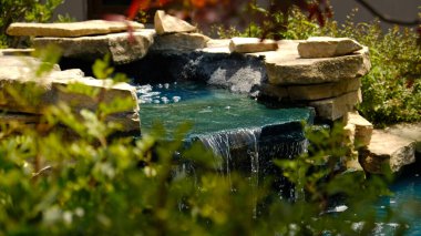 Geleneksel bir Japon bahçesinde mini bir şelale. Taşlardan yapılmış dekoratif şelale ve peyzaj tasarımı için küçük bir gölet.