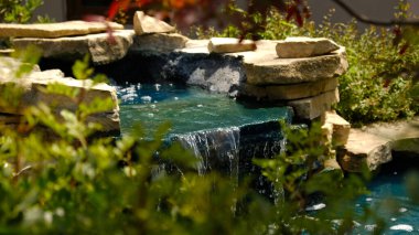 Geleneksel bir Japon bahçesinde mini bir şelale. Taşlardan yapılmış dekoratif şelale ve peyzaj tasarımı için küçük bir gölet.