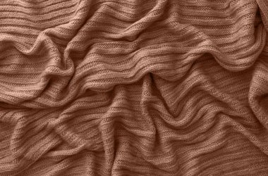 Kahverengi örülmüş atkı ya da süveter deseni, üst manzara. Sıcak örülmüş tekstil kumaşının dokusu. Örgü kumaş. 2025 'in Mocha Mousse Rengi.