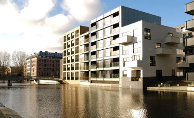 Balkonları Hollanda 'daki bir kanalın sakin sularına yansıyan modern apartman binası. Kentsel yaşam, çağdaş Hollanda mimarisi, şehir manzarası.