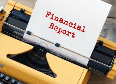 Finansal rapor olarak etiketlenmiş bir kağıt parçasına sahip sarı bir daktilo klasik bir ofis ekipmanıdır.