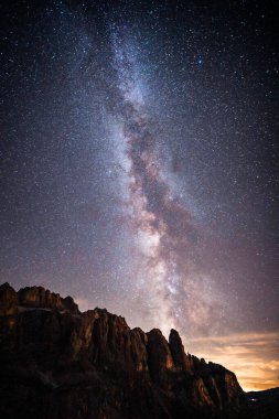 Sayısız yıldızla dolu çarpıcı bir gece gökyüzü bu güzel manzaranın ön planında duran görkemli bir dağı aydınlatıyor.