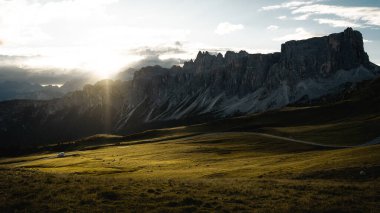 Güneş ışıl ışıl parlıyor Uzaktaki görkemli dağların üzerinde süzülen kabarık bulutların arasından