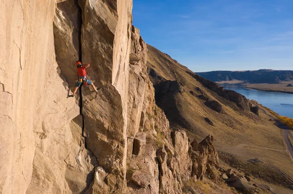 Man Climber Rock Climbing. Crack Trad Climbing. Cliffs in Tamgaly Tas, Kazakhstan. River and Steppe. Aerial View.