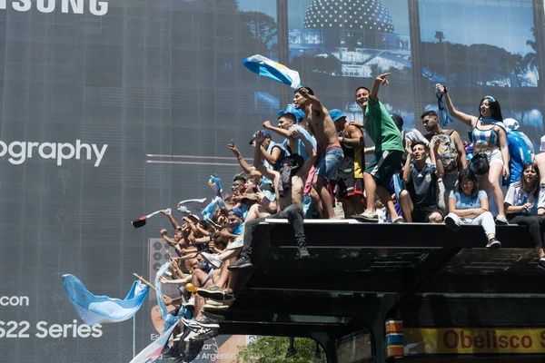 BUENOS AIRES, ARGENTINA - 20 Aralık 2022: FIFA Dünya Kupası Katar 2022 'de Arjantin Futbol Takımı Zaferinin Kutlanması sırasında Metrobus İstasyonu' nun tepesinde Dans, Şarkı Söyleyen ve Bayrak Sallayan Hayranlar.