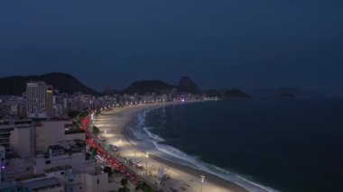 Rio de Janeiro City at Night. Copacabana Beach and Atlantic Ocean. Evening Twilight. Blue Hour. Aerial View. Brazil. Drone Flies Forward over Avenida Atlantica
