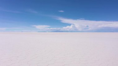 Güneşli bir günde Uyuni Tuz Düzlükleri 'ne bakan kendine güvenen gezgin. Hava görüntüsü. Altiplano, Bolivya. Kurak Mevsim. Tuz çatlakları ve oluşumları. İHA Alçak Seviyede Uçuyor. Solo Seyahat Konsepti