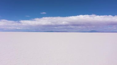 Güneşli bir günde Uyuni Tuz Düzlükleri. Salar De Uyuni. Hava görüntüsü. Altiplano, Bolivya. Kurak Mevsim. Altıgen Tuz oluşumları ve Çatlak desenleri. İHA alçaktan geriye doğru uçuyor. Geniş Görüntü