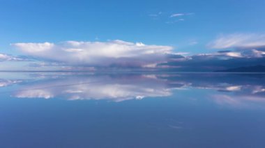 Güneşli bir günde Uyuni Tuz Düzlükleri. Salar de Uyuni. Hava görüntüsü. Altiplano, Bolivya. Yağmur mevsimi. Göl yüzeyinde Bulutların Yansıması. İnsansız hava aracı yukarı ve geri uçuyor. Geniş Görüntü