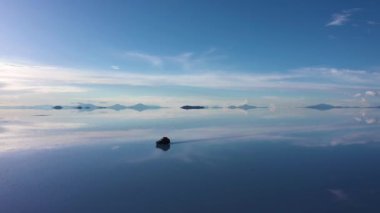 Güneşli bir günde Uyuni Tuz Düzlükleri. Salar De Uyuni. Hava görüntüsü. Altiplano, Bolivya. Islak Mevsim. SUV arabası. Göl yüzeyinde Bulutların Yansıması. Yörüngede