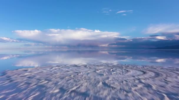 ウユニ塩フラッツ 空中展望 ボリビアのアルティプラノ 雨季だ 湖表面の水に雲の反射 ドローンは低レベルで前進します ワイドショット — ストック動画