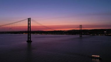 Ponte 25 de Abril Askılık Köprüsü Lizbon 'u Almada' ya bağlıyor. Akşam Alacakaranlığı, Mavi Saat. Portekiz. Hava görüntüsü. İnsansız Hava Aracı Yana ve Yukarı Uçar