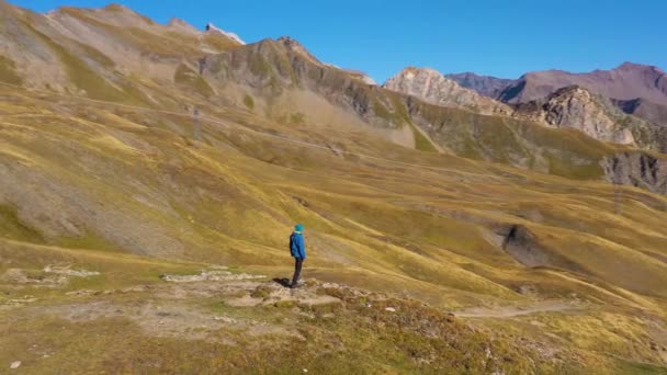 ブルージャケットのハイカーマンが山を眺めている ヒルズと山々 クロワイス ボナムス フランスアルプス フランス アリアルビュー オービット ミディアムショット — ストック動画