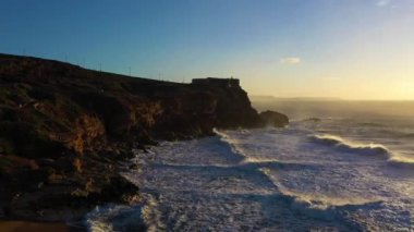 North Beach, Cliffs, Fort and Atlantic Ocean Sunset 'te. Nazare, Portekiz. Büyük Dalgalar. Hava görüntüsü. Drone Geriye Uçuyor