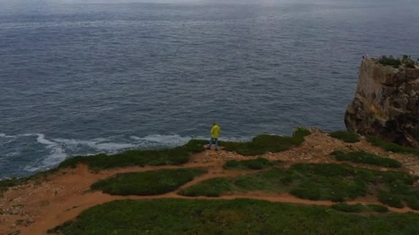 Lonely Man Yellow Jacket Está Borda Penhasco Olhando Para Oceano — Vídeo de Stock