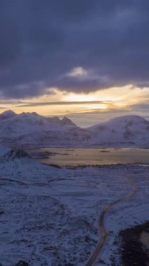 Yol, kışın Sunset 'te Deniz Kıyısı ve Dağlar. Flakstadoya, Lofoten Adaları, Norveç manzarası. Hava Hızı Hızı, Zaman Hızı. Drone İleri Uçuyor. Dikey Video