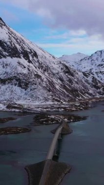Fredvang Cantilever Köprüsü, Fjord ve Volandstind Dağı, kışın. Flakstadoya, Lofoten Adaları, Norveç manzarası. Hava görüntüsü. Drone yörüngede. Dikey Video