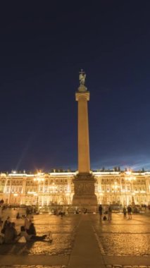 SAINT-PETERSBURG, RUSSIA - 24 Haziran 2019: Palace Square, Alexander Column, Aydınlatılmış Kış Sarayı ve Yaz Gecesindeki İnsanlar. Motion Panning Time Lapse... dikey Video