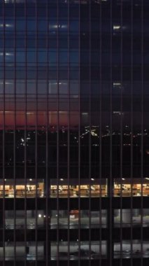 JERSEY CITY, ABD - 23 HAZİRAN 2021: Goldman Sachs Tower Skyscraper at Night. Camdaki yansıma. Mavi Saat. Hava görüntüsü. ABD. Drone yukarı doğru uçuyor. Dikey Video
