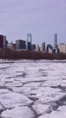 Chicago 'nun Kentsel Skyline ve Donmuş Göl Michigan Kış Frosty Günü' nde buz bloklarıyla. Hava görüntüsü. Amerika Birleşik Devletleri. İnsansız hava aracı yandan uçuyor. Kaydırıcı Düşük Seviye Atışı. Dikey Video