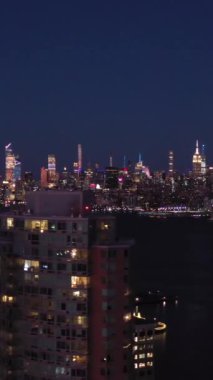 JERSEY CITY, ABD - 23 HAZİRAN 2021: Kentsel Manhattan New York ve Jersey City Skyline at Night. Hava görüntüsü. ABD. Drone Yana ve Yukarı Uçuyor. Dikey Video