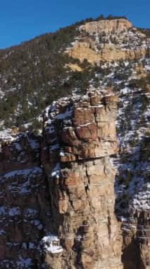Güneşli kış gününde Kale Kapısı Kulesi. Dağlar ve yol. Utah, ABD. Hava görüntüsü. Drone yörüngede. Dikey Video