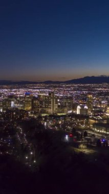 Kış gecelerinde Salt Lake City Skyline 'ı aydınlattı. Kongre Binası Tepesi. Utah, ABD. Hava Hızı Hızı, Zaman Hızı. Mavi Saat. Drone ileri ve aşağı uçuyor. Dikey Video