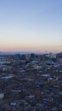 Sabah alacakaranlıkta Salt Lake City Skyline ve kışın dağları. Liberty Park 'ın manzarası. Utah, ABD. Hava Hızı Hızı, Zaman Hızı. Drone İleri Uçuyor. Dikey Video