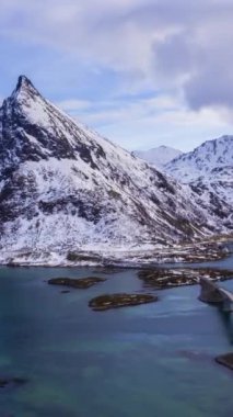 Fredvang Köprüsü ve Volandstind Dağı, kışın. Flakstadoya, Lofoten Adaları, Norveç manzarası. Hava Hızı Hızı, Zaman Hızı. Drone ileri ve yukarı doğru uçuyor. Dikey Video