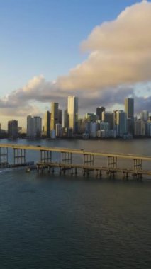 Miami, Sunset 'te. Şehir merkezi ve Rickenbacker Geçidi. Altın Saat. Kentsel Şehir Manzarası. Hava Hızı Hızı, Zaman Hızı. Florida, ABD. Drone ileri ve yukarı doğru uçuyor. Dikey Video