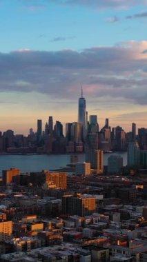 Aşağı Manhattan, Jersey City ve Hudson Nehri. New York, Sunset 'te. Binalarda güneş ışığı. Hava görüntüsü. Amerika Birleşik Devletleri. Drone Yana ve Yukarı Uçuyor. Dikey Video