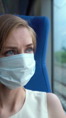 Coronavirus Covid-19 pandemisi sırasında Maskeli Genç Kafkas Kadın Şehirde Trende Pencere 'ye bakıyor. Dikey Video