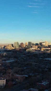 Güneşli bir günde Salt Lake City ve kışın Dağlar. Liberty Park 'ın manzarası. Utah, ABD. Hava görüntüsü. İnsansız hava aracı yukarı ve geri uçuyor. Dikey Video