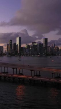 Miami, Akşam Alacakaranlığı 'nda. City Skyline ve Rickenbacker Geçidi. Mavi Saat. Kentsel Şehir Manzarası. Hava görüntüsü. Florida, ABD. Drone Yana ve Yukarı Uçuyor. Dikey Video
