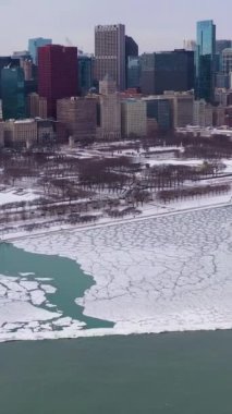 Chicago 'nun Kentsel Skyline ve Donmuş Göl Michigan Kış Dondurma Günü' nde Ice Lumps ile. Hava görüntüsü. Amerika Birleşik Devletleri. İnsansız Hava Aracı Yana Uçuyor, Eğil. Dikey Video
