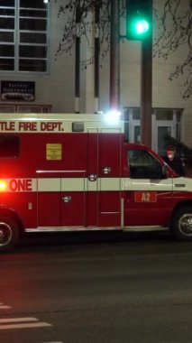 SEATTLE, ABD - 4 Şubat 2021: Seattle İtfaiye Departmanı, Geceleri Parlayan Işıklı Ambulans Aracı. Maske takan insanlar. Dikey Video