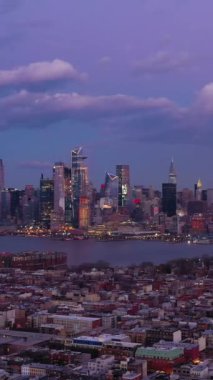 Manhattan Şehir Merkezi, Hoboken ve Hudson Nehri Akşam Alacakaranlığı 'nda. New York City, ABD. Hava görüntüsü. İnsansız hava aracı yandan uçuyor. Dikey Video