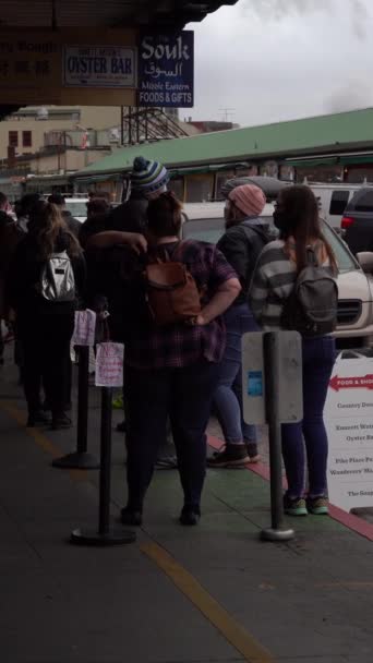 米国シアトル February 2021 マスクを着用する人々はサイドウォークに並び コヴィド 19パンデミック中にカフェに入るのを待っている社会的距離を実践しています パイク プレイス バーティカルビデオ — ストック動画