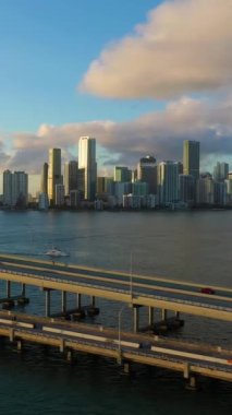Miami, Sunset 'te. City Skyline ve Rickenbacker Geçidi. Altın Saat. Kentsel Şehir Manzarası. Hava görüntüsü. Florida, ABD. Drone Yana ve Yukarı Uçuyor. Dikey Video