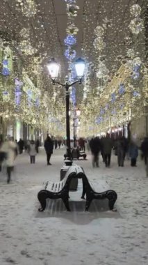 MOSCOW, RUSSIA - 25 Aralık 2020: Aydınlanmış Nikolskaya Pedestrian Caddesi 'nin Zaman Geçidi. Kış akşamında yürüyen insanlar. Noel tatilleri. Moskova, Rusya... dikey video