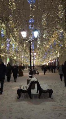 MOSCOW, RUSSIA - 25 Aralık 2020: Nikolskaya Yayası Caddesi 'ni aydınlattı. Kış akşamında yürüyen insanlar. Noel tatilleri. Moskova, Rusya... dikey video