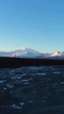 Chulitna Nehri ve Sunset 'teki Denali Dağı. Alaska manzarası, ABD. Hava görüntüsü. İHA, Alçak Seviye 'de nehrin üzerinden geriye doğru uçuyor. Dikey Video