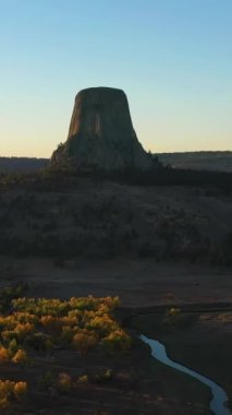 Sonbaharda Sunset 'te Şeytan Kulesi Butte ve Belle Fourche Nehri. Crook County 'de. Wyoming, ABD. Hava görüntüsü. Drone yörüngede. Dikey Video